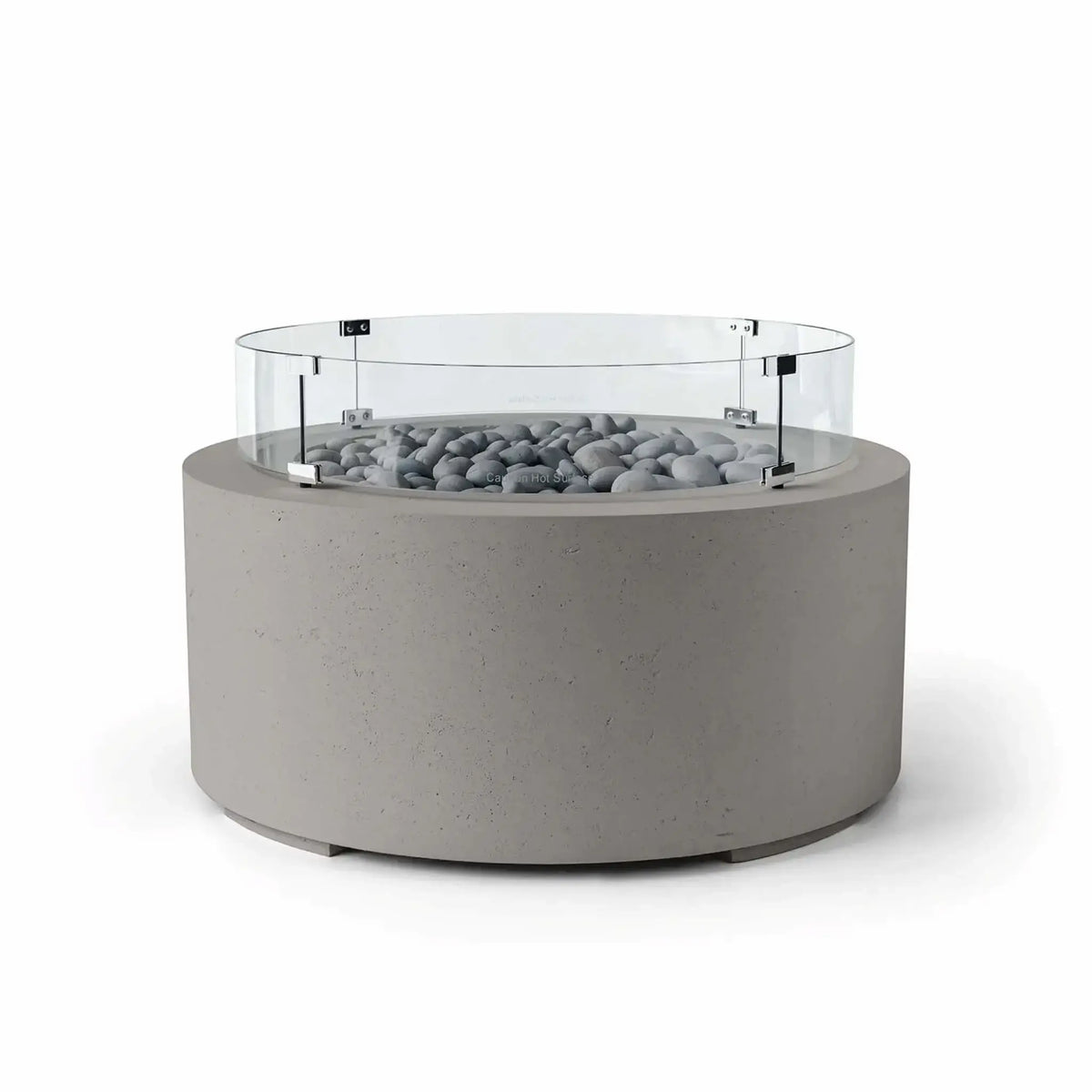 HPC Fire Hearth Products Controls Dekko GFRC Concrete Belmont Fire Pit in Sandstone finish with Slate Stone fire media and a Tempered Glass Wind Guard. This modern round fire pit features a warm beige concrete body, smooth gray slate stones surrounding the burner area, and a clear circular glass windscreen designed for enhanced flame protection. The Belmont Fire Pit serves as an elegant outdoor centerpiece for patios, terraces, and lounge areas.