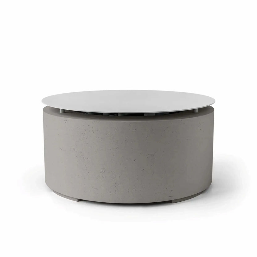 HPC Fire Hearth Products Controls Dekko GFRC Concrete Belmont Fire Pit in Sandstone finish with integrated Table Top Lid. This modern outdoor fire pit showcases a neutral sandstone-gray concrete finish, durable GFRC construction, and a circular cover that conceals the fire media area when not in use. The Belmont Fire Pit delivers both decorative appeal and practical tabletop functionality for upscale outdoor living environments.
