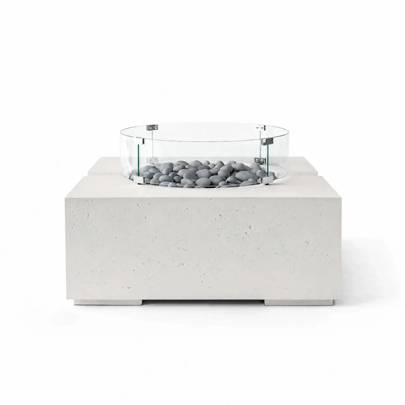 HPC Fire Hearth Products Controls Dekko GFRC Concrete Bravo 32 x 32 Fire Pit in Ash finish featuring Slate Stone fire media and a clear tempered glass wind guard. The contemporary square fire pit displays a textured concrete exterior, recessed burner area, and smooth gray decorative stones, creating a modern outdoor centerpiece presented on a white background.