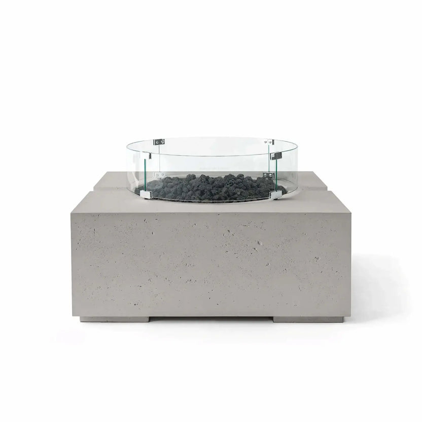 HPC Fire Hearth Products Controls Dekko GFRC Concrete Bravo 32 x 32 Fire Pit in Sandstone finish featuring black lava rock fire media and a tempered glass wind guard. The warm-toned GFRC concrete body contrasts with the dark volcanic rock, highlighting the fire pit’s clean geometric form, textured finish, and upscale outdoor entertainment appeal.