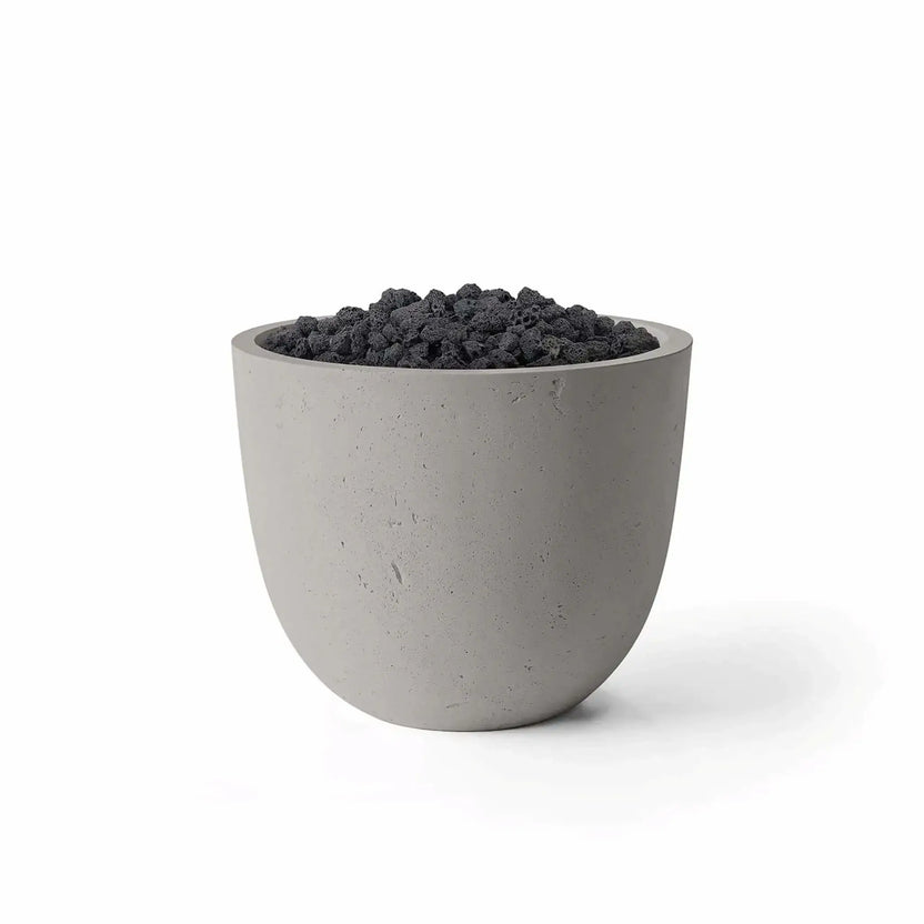 Dekko GFRC Concrete Element 20 Round Fire Column by HPC in a Sandstone finish paired with black Lava Rock media. The contemporary fire column features a rounded GFRC concrete exterior with a warm sandstone tone and a recessed burner area filled with natural volcanic rock. Studio product image on a white background highlighting the Sandstone finish, textured concrete surface, and rugged Lava Rock fire media.