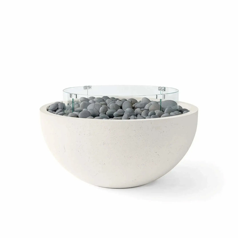 HPC Fire Hearth Products Controls Dekko GFRC Concrete Serenade 32 Fire Pit in Limestone finish with smooth slate stone media and a tempered glass wind guard. This modern outdoor fire bowl features a rounded GFRC concrete body, subtle stone-textured finish, and decorative gray river stones that complement contemporary patios, courtyards, outdoor seating areas, and luxury landscape designs.