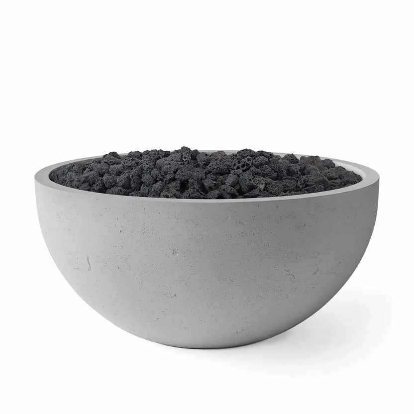 HPC Fire Hearth Products Controls Dekko GFRC Concrete Serenade 40 Fire Pit in Charcoal finish with black lava rock media. This round GFRC concrete fire bowl features a rich gray textured surface, broad circular opening, and rugged volcanic rock fill. Studio product image showcases the modern outdoor fire pit design, emphasizing durability, clean lines, and the dramatic contrast between the charcoal concrete finish and dark fire media.