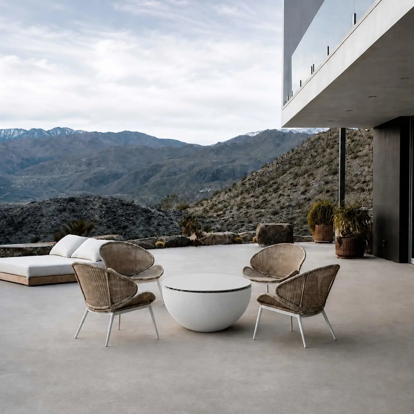 HPC Fire Hearth Products Controls Dekko GFRC Concrete Serenade 40 Fire Pit Table Top Lid featured on a luxury outdoor patio overlooking a mountain landscape. Positioned between four woven lounge chairs, the covered fire pit functions as a modern coffee table while maintaining the clean architectural style of the contemporary home. The tabletop lid provides a practical surface and protects the fire feature when not in use.