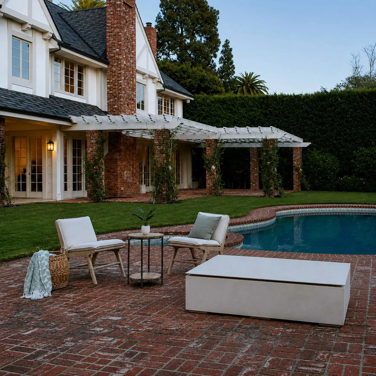 HPC Fire & Hearth Products Controls Dekko GFRC Concrete Sonoma 72 x 33 Fire Pit Table Top Lid featured on a brick poolside patio beside cushioned lounge chairs and a swimming pool. The fire pit’s matching lid transforms the unit into a stylish outdoor coffee table, complementing the traditional architecture and landscaped backyard setting. The clean rectangular design enhances functionality while maintaining a refined outdoor living aesthetic.
