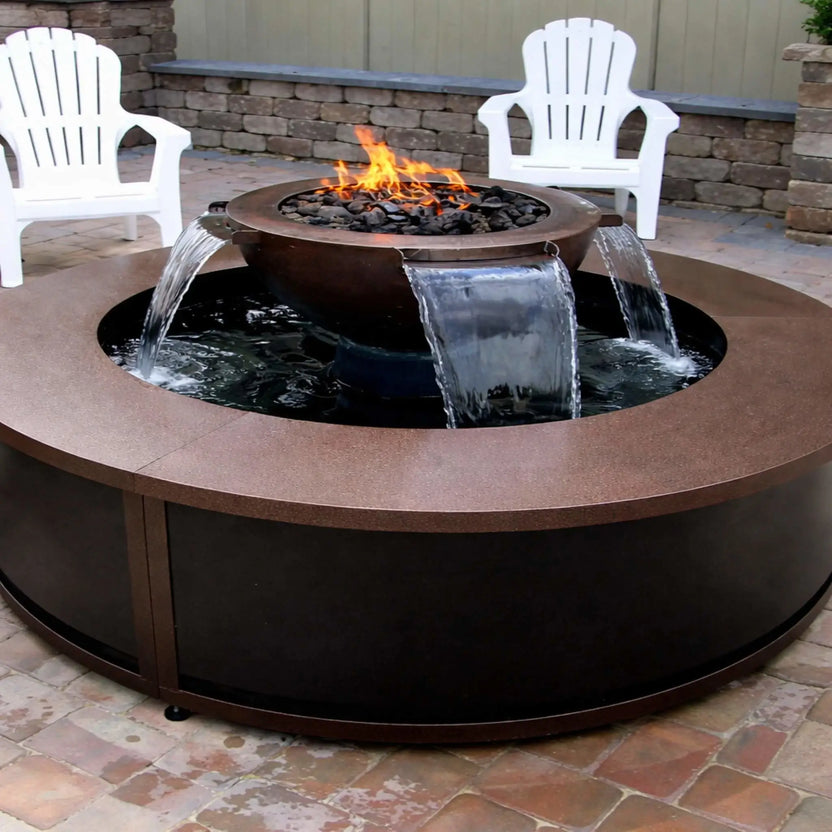 Outdoor patio installation of the HPC Fire Evolution 360 fire and water feature with a round table-style enclosure. Water flows evenly from multiple scuppers into the surrounding basin while a gas flame burns above black lava rock. White Adirondack chairs and a stone retaining wall create a relaxed backyard setting.