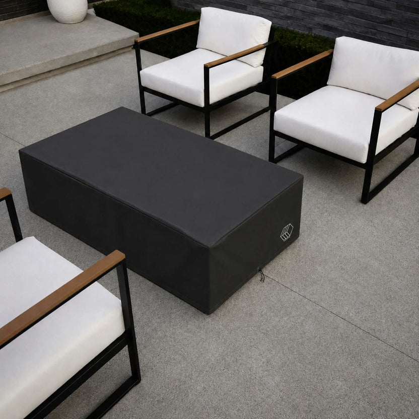 HPC Fire Hearth Products Controls GFRC Concrete Sonoma 56 x 30 Weather Cover Lifestyle 2 image featuring a top-down view of the black weather cover installed on a Sonoma fire pit. Positioned among modern outdoor seating with white cushions and black metal frames, the cover fully encloses the fire feature to shield it from outdoor elements. The image highlights the cover’s tailored fit, durable construction, and sleek appearance within a luxury patio setting.