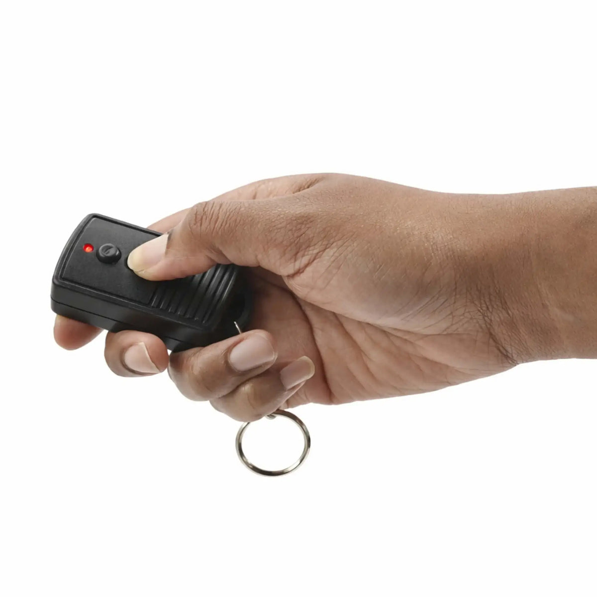 Lifestyle image showing a person holding a black handheld on/off remote control with a keyring attachment, actively pressing one of the buttons. The remote features a red LED indicator light and textured grip, demonstrating ease of use and portability for controlling a fire pit or fireplace system.