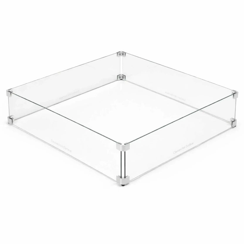 Square tempered glass fire pit wind guard displayed on a clean white background, featuring clear panels joined with polished metal corner brackets and raised support feet. This minimalist design highlights the protective barrier that shields flames from wind while maintaining a sleek, modern look for outdoor gas fire pit installations.