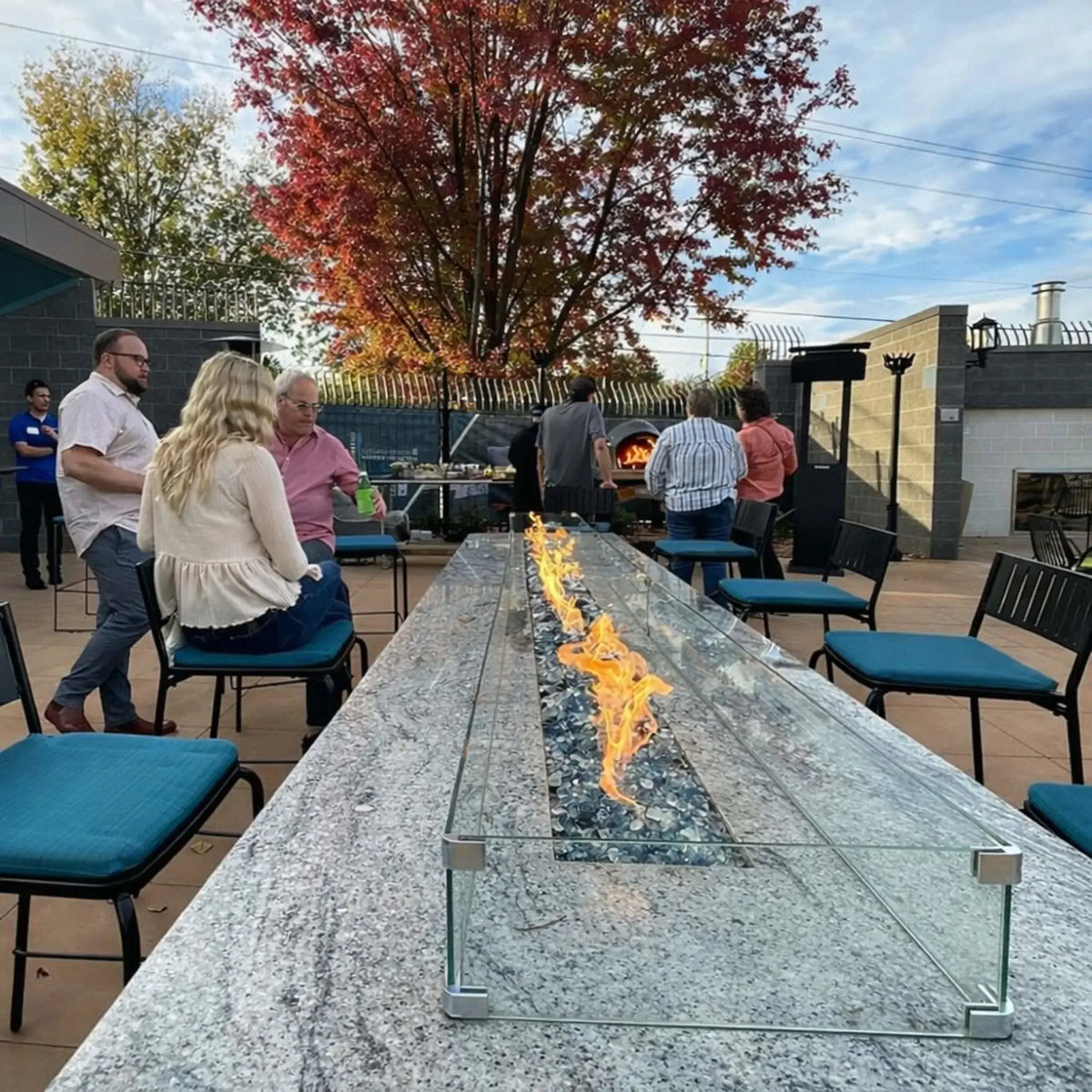 Front-facing view of a stone linear fire pit featuring HPC Fire Hearth Products Torpedo Linear burner system, with visible flame channel, lava rock media, and durable masonry construction for outdoor patio installations.