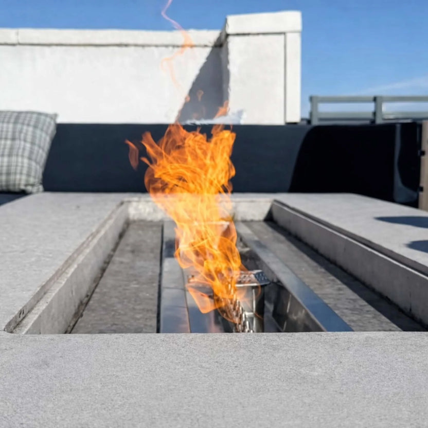 Detailed view of the HPC Torpedo Linear Trough Pan and T Burner flame rising from a recessed concrete fire feature, showcasing the internal burner structure and clean linear channel design in a contemporary outdoor space.