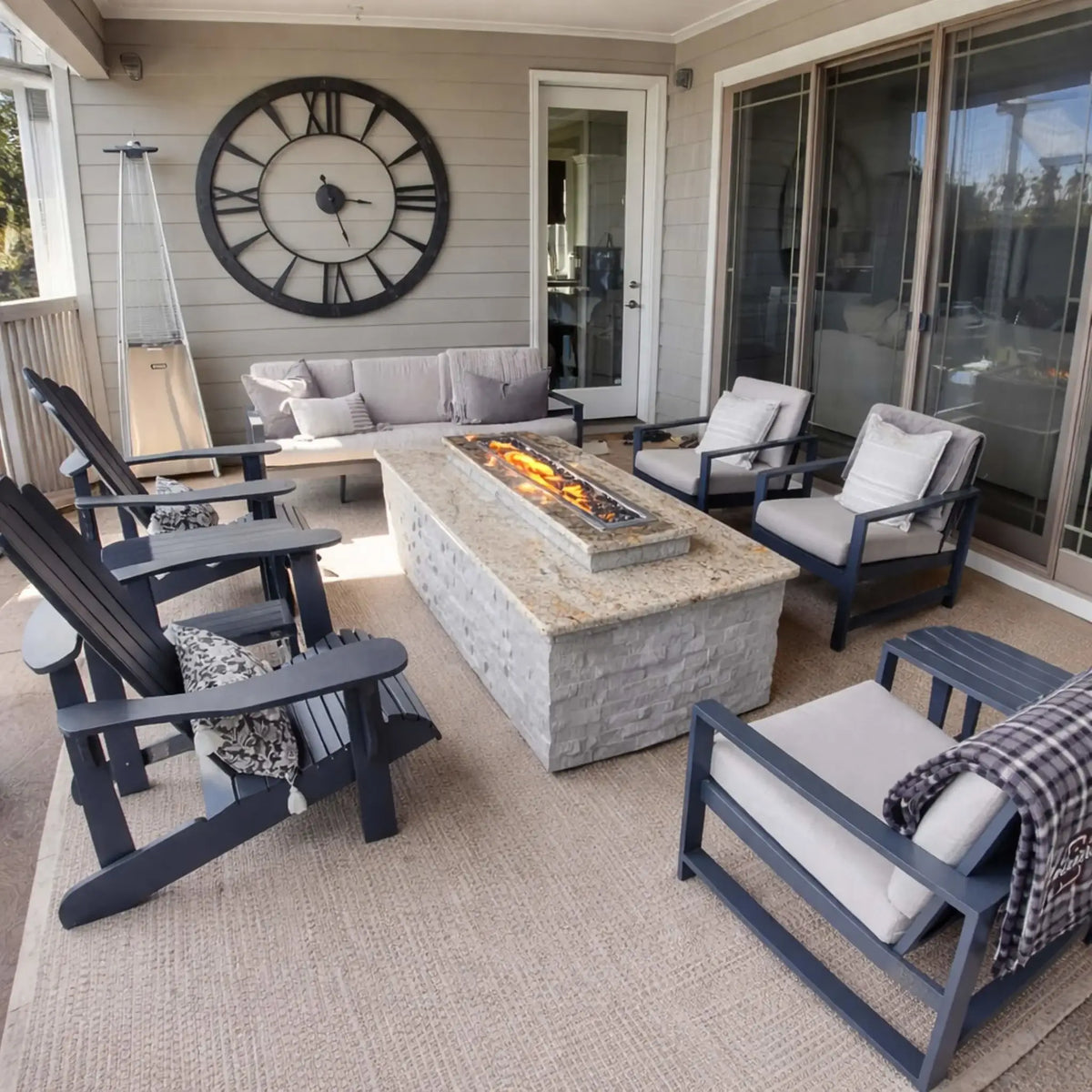 Covered patio seating area with a central fire table powered by the HPC Fire Hearth Products Torpedo Linear Trough Pan and T Burner Match Lit CSA MLFPK FLEX system. The linear flame feature provides steady warmth and ambiance, while the CSA match lit system emphasizes ease of use, quick lighting, and dependable performance for relaxed outdoor gatherings.