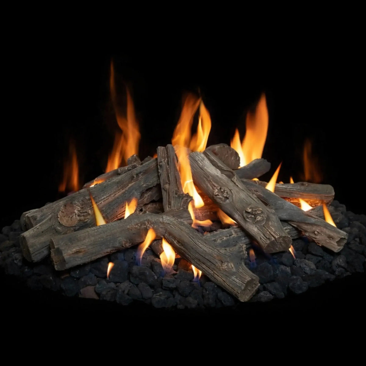 Western driftwood gas fire pit logs arranged over black lava rock with bright yellow-orange flames rising between the logs. The realistic wood grain and charred detailing enhance the natural campfire appearance, set against a dark background that emphasizes the flame movement and glowing ember effect.