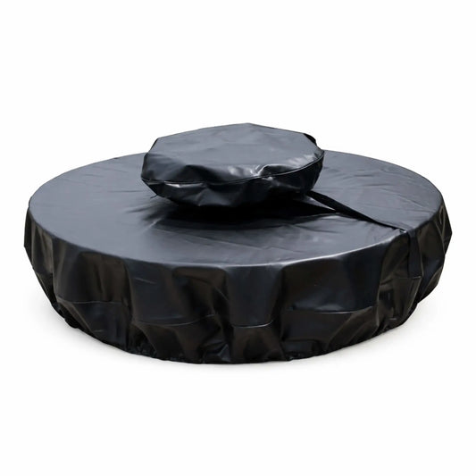 Round black vinyl fire pit cover designed for a unit with a raised center section, shown on a white background. The cover features a two-tier fit with a smaller, elevated top section and a wider base cover, connected by a visible strap or seam. The material has a smooth, slightly glossy finish with natural creases and folds, while the lower edge appears gathered for a snug, secure fit, offering full protection from weather and debris.