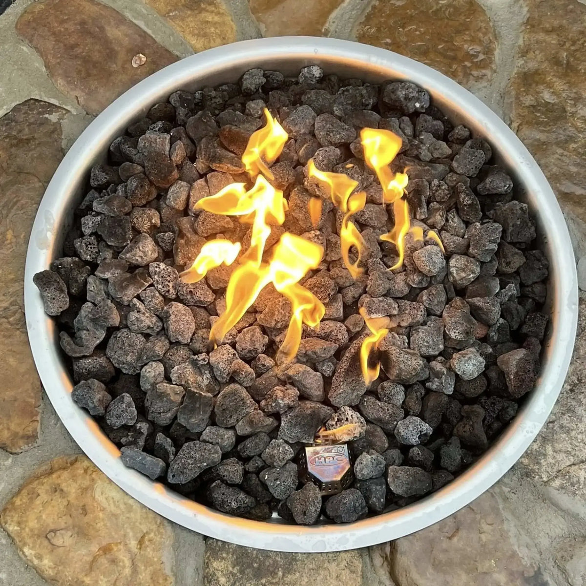 HPC Fire Inspired Hearth Products electronic ignition penta burner top-down view showing active flames over black lava rock inside a circular fire pit insert. The stainless steel rim is visible around the edge, highlighting flame pattern, ignition point, and clean drop-in installation design.