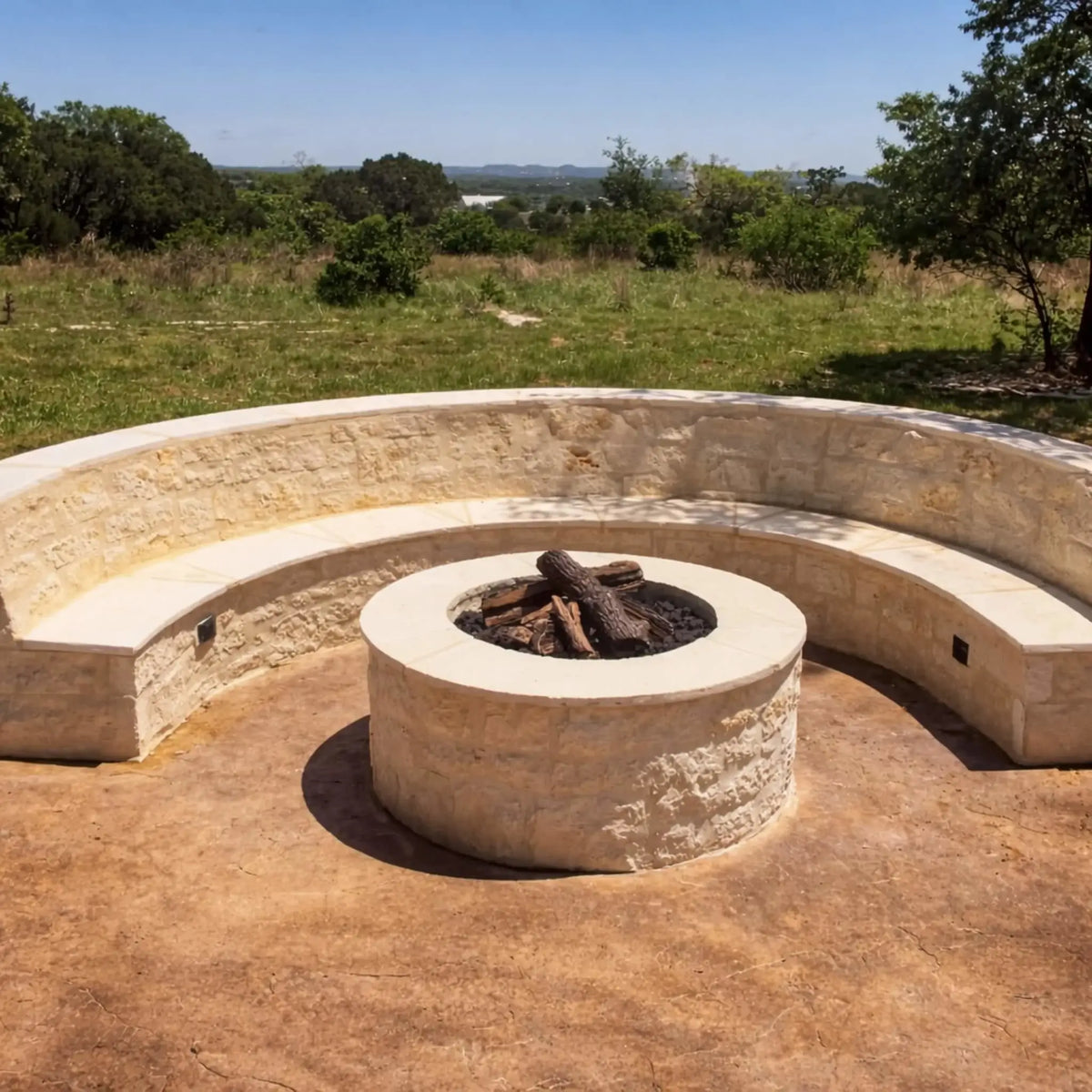 HPC Fire Inspired Hearth Products round flat match lit CSA MLFPK FLEX standard torpedo penta burner integrated into a curved stone seating area. The central round fire pit is surrounded by built-in bench seating in a scenic open landscape, showcasing a custom-designed outdoor gathering space with natural stone finishes.
