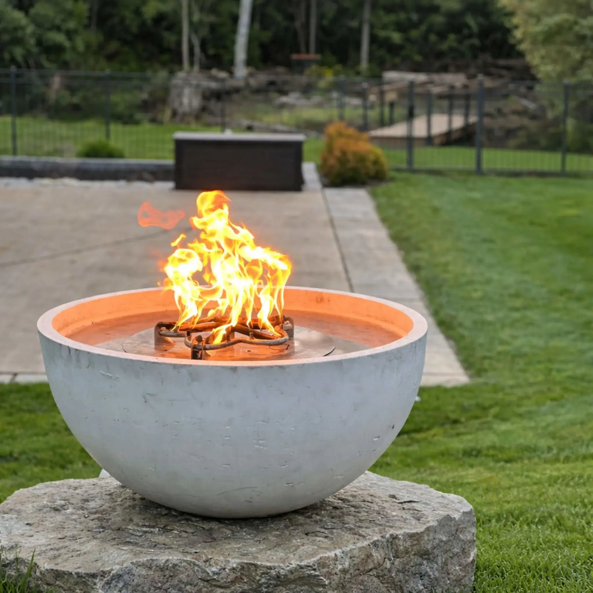 HPC Fire Inspired Hearth Products round flat match lit CSA MLFPK FLEX standard torpedo penta burner featured in a backyard patio with a round fire pit surrounded by curved red-cushion seating. A pool, pergola, and landscaped yard complete the setting, showcasing a high-end outdoor living design.