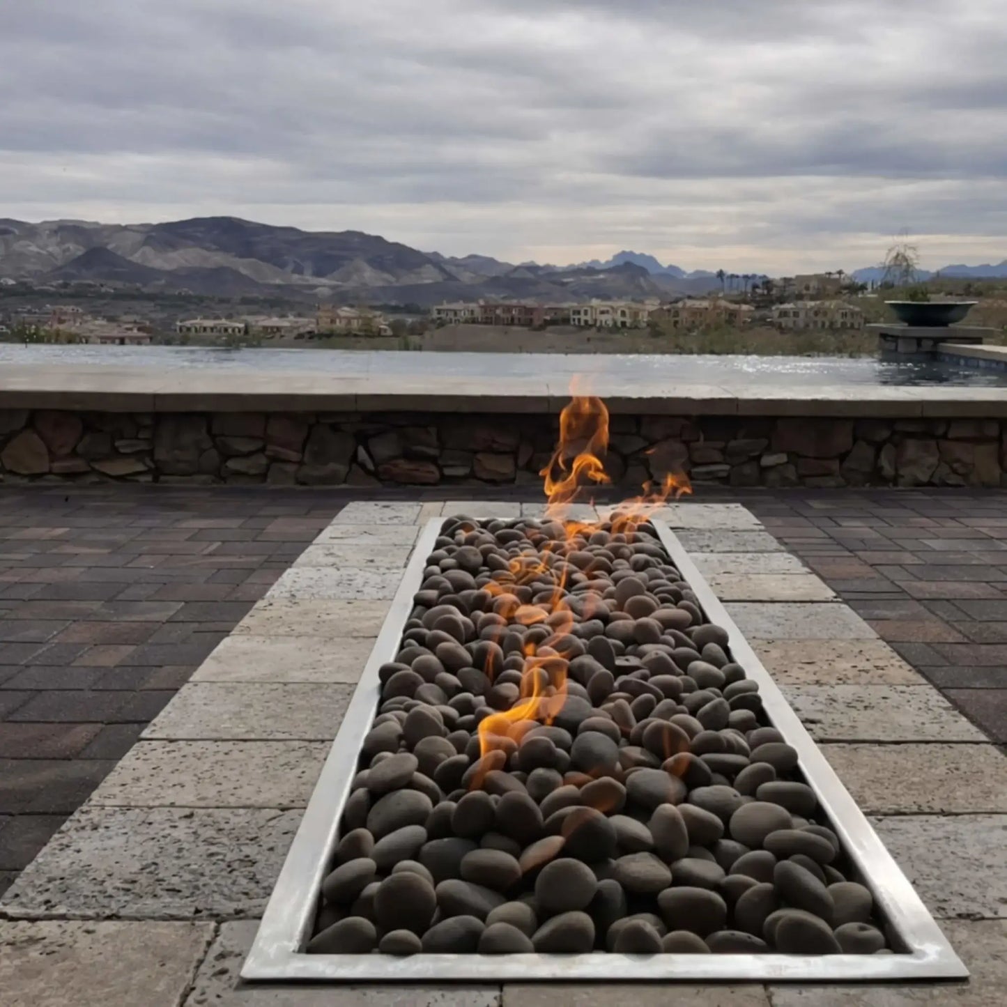 Hearth Products Controls HPC Fire rectangle drop in pan H burner torpedo electronic ignition Hi Lo low commercial patio seating area with large rectangular fire table and glass wind guard, surrounded by modern chairs, designed for easy operation using remote or app with high and low flame settings.