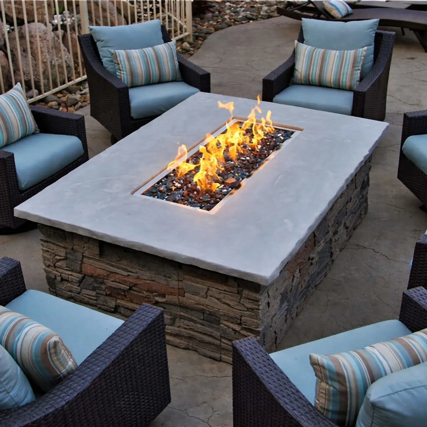 Square stone fire pit table showcasing HPC Fire Rectangle Drop-In Pan H Burner Torpedo Match Lit (CSA MLFPK Flex) with black fire glass, surrounded by cushioned outdoor chairs in a circular patio layout, highlighting a clean, modern backyard design.