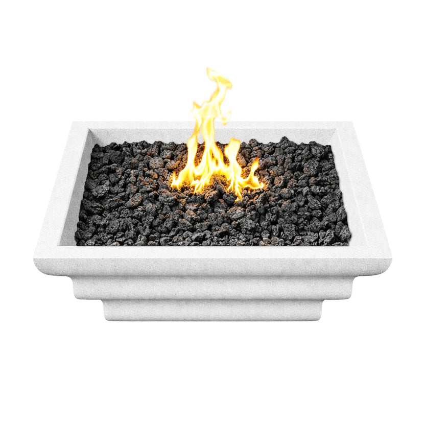 Top-down view of the white Shadow Cast Ripple Designer Series fire bowl filled with black lava rock media and a bright yellow flame rising from the center burner. The square rim frames the fire media evenly, while the clean white textured finish highlights the modern design of this outdoor gas fire pit bowl.