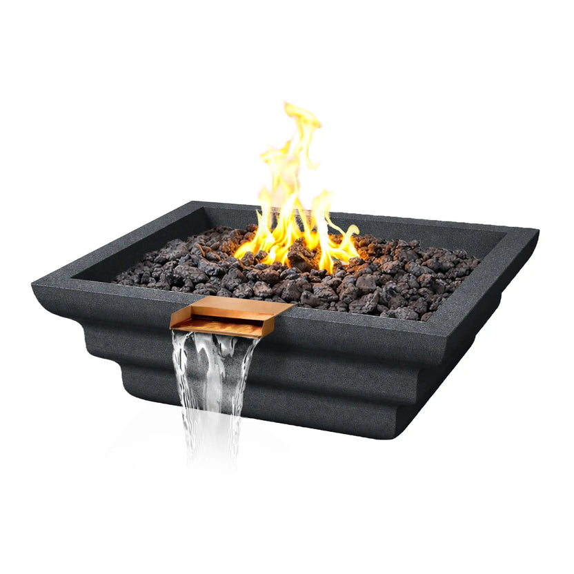 Angled product view of a graphite Shadow Cast Ripple Designer Series fire and water bowl by Flame Havens. A bright yellow gas flame rises from black lava rock fire media while a copper waterfall spillway releases a smooth sheet of flowing water from the front edge. The GFRC concrete bowl features a sculpted ripple exterior profile and modern square design.