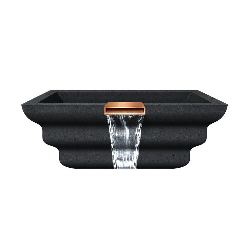Side profile view of the graphite Shadow Cast Ripple fire and water bowl showing the sculpted stepped exterior design and integrated copper waterfall spillway. Water flows smoothly from the spillway while the basin remains empty, emphasizing the GFRC concrete construction and architectural ripple texture.