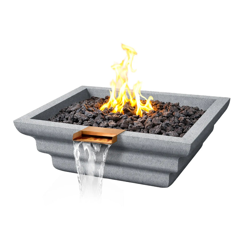 Angled product view of the gray Shadow Cast Ripple Designer Series fire and water bowl by Flame Havens. A lively gas flame burns above dark lava rock media while water flows from a copper waterfall spillway. The light gray GFRC concrete bowl features a modern square shape with layered ripple detailing along the exterior.