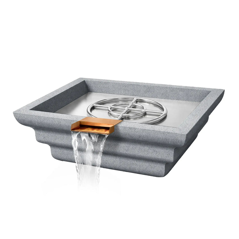 Angled product view of a gray Shadow Cast Ripple Designer Series fire and water bowl by Flame Havens. The square GFRC concrete bowl features a stepped ripple exterior and a copper waterfall spillway at the front releasing a smooth sheet of water. Inside the basin, a stainless steel burner ring and support structure sit within a metal burner pan, showing the internal fire system without flame active.