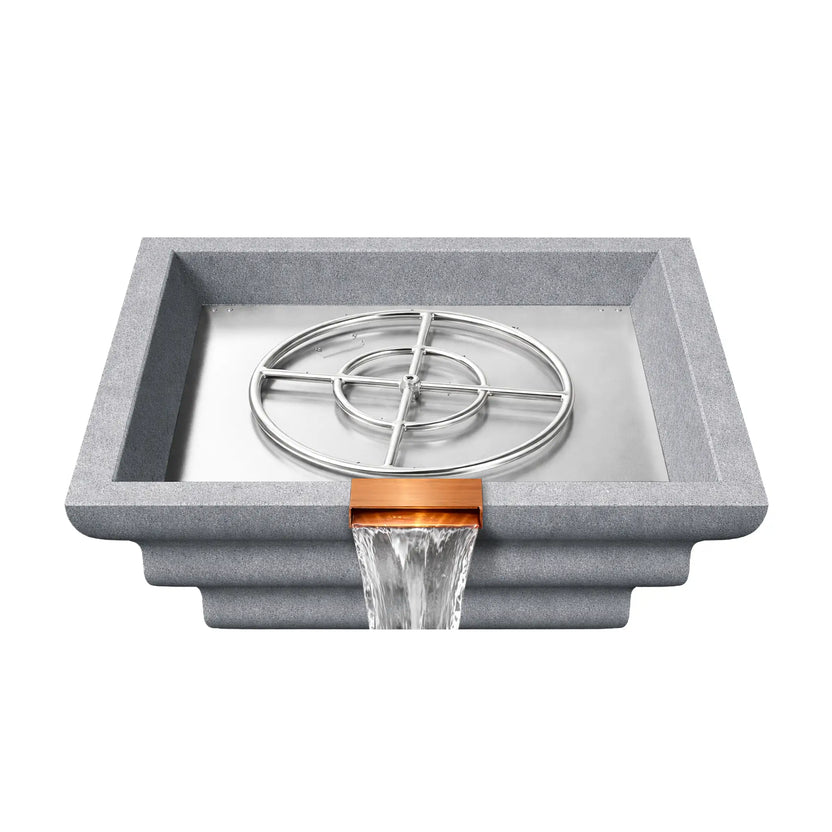 Overhead view of a gray Shadow Cast Ripple fire and water bowl with the stainless steel burner ring assembly exposed inside the metal burner tray. The basin is empty of fire media while water flows from the copper waterfall spillway, revealing the internal fire feature components used to create the gas flame.