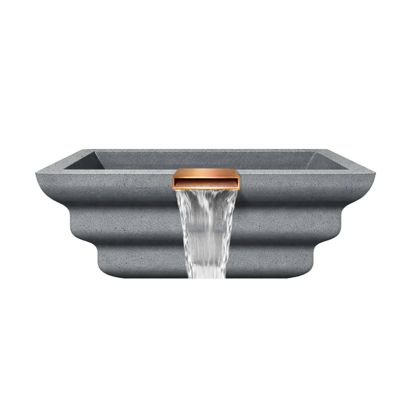 Side profile view of the gray Shadow Cast Ripple fire and water bowl showing the layered ripple-style GFRC concrete exterior. Water pours steadily from the copper waterfall spillway while the basin remains empty, emphasizing the sculpted bowl shape and decorative architectural profile designed for poolside installations.