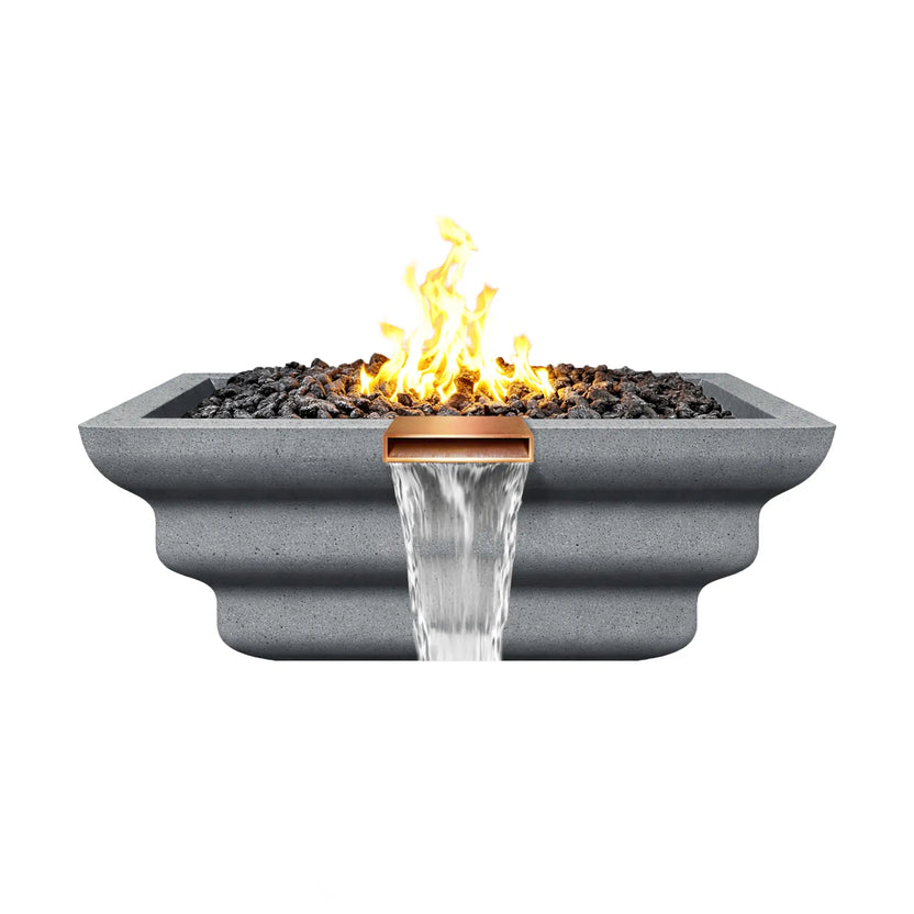 Side view of a gray Shadow Cast Ripple Designer Series fire and water bowl with a lively gas flame rising above black lava rock media. A copper spillway releases a smooth waterfall below the fire bowl while the stepped ripple exterior design adds texture to the GFRC concrete structure.
