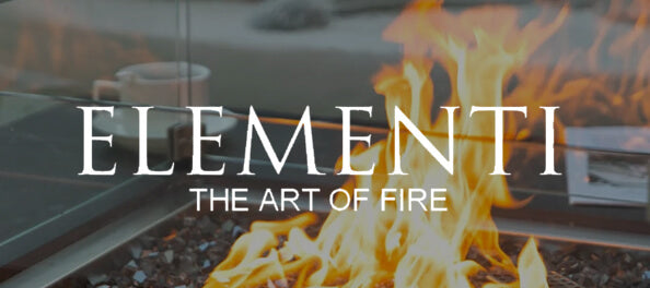 A promotional graphic with large white text reading 'ELEMENTI' and smaller text 'THE ART OF FIRE' over a blurred fire scene. The background shows a fire pit or outdoor fire feature with visible flames, dark metal rails, and a glass panel.